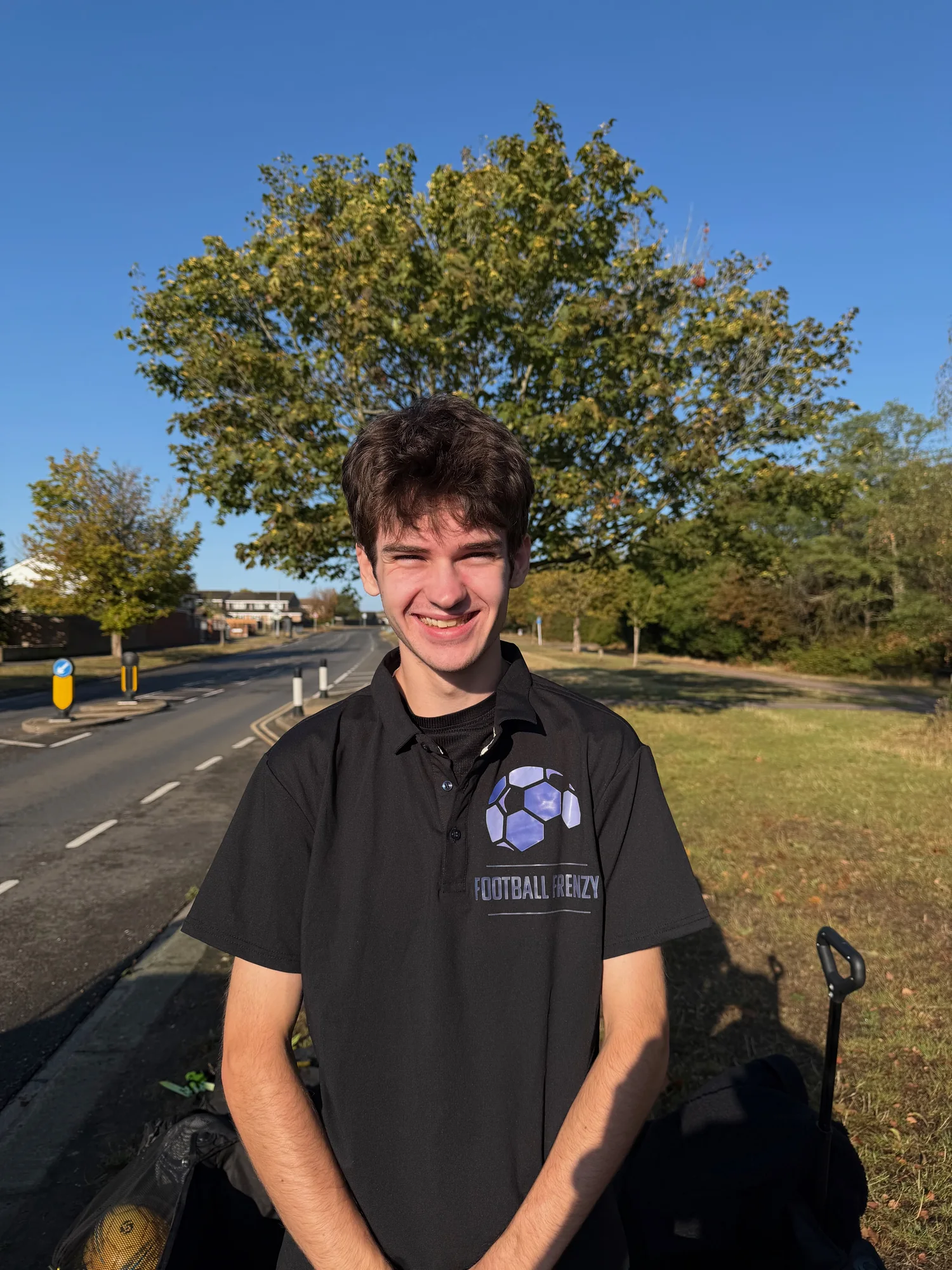 Coach Andrew smiling in his black Football Frenzy polo shirt